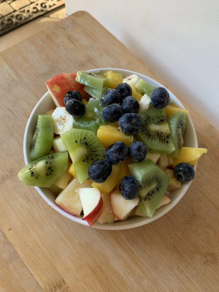 a white bowl filled with fruit on top of a wooden table