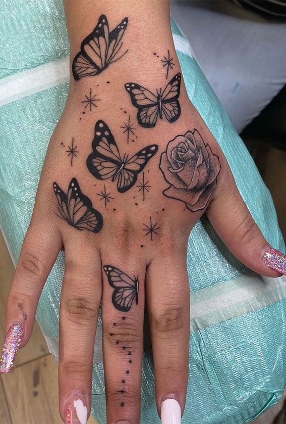 a woman's hand with butterflies and roses tattooed on the middle of her palm