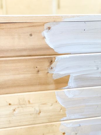 white paint is being applied on the side of a wooden wall