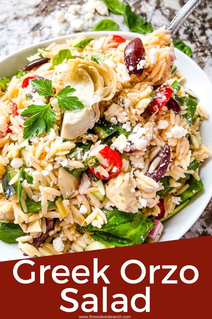 greek salad with chicken and feta cheese in a white bowl on a marble table