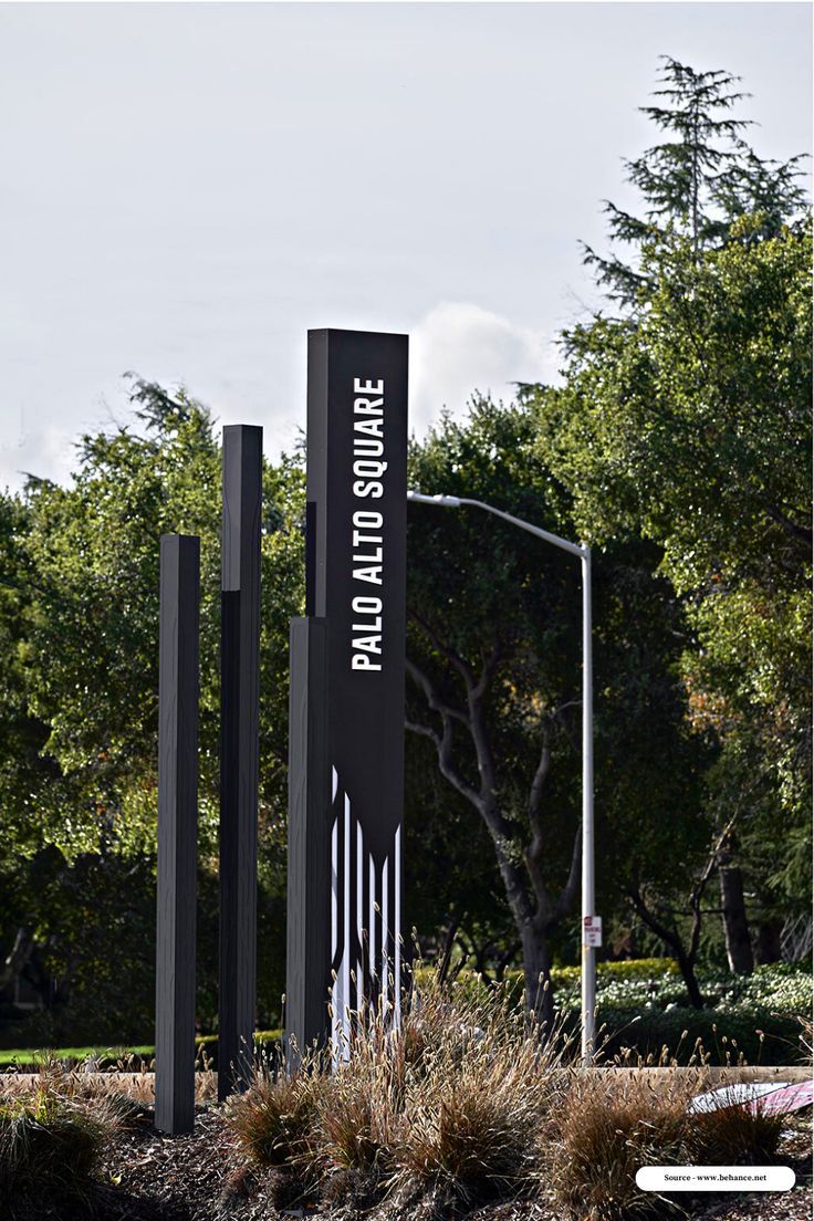 three black and white signs in front of some trees on a sunny day with no clouds