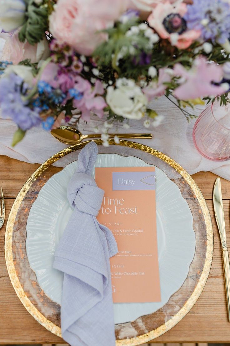 the table is set with an elegant pink and blue centerpiece, silverware, and napkins