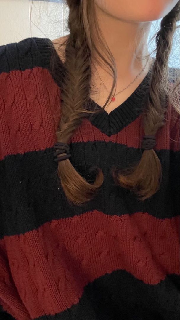 a woman with long hair wearing a red and black striped sweater