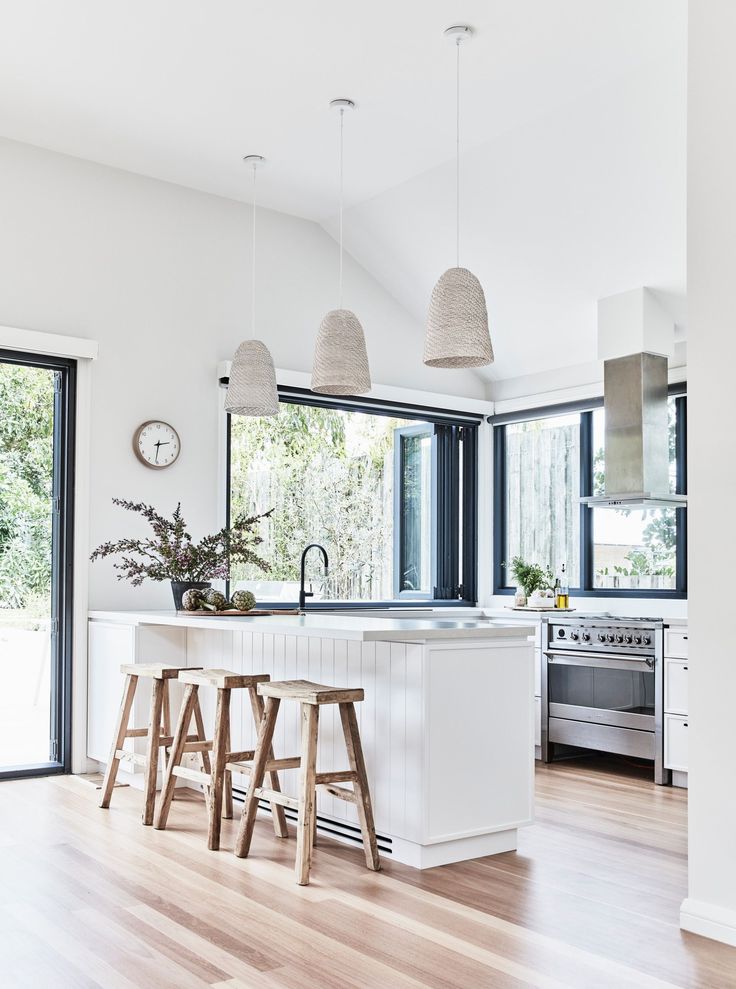 a kitchen with two stools in front of an island and three lights hanging from the ceiling