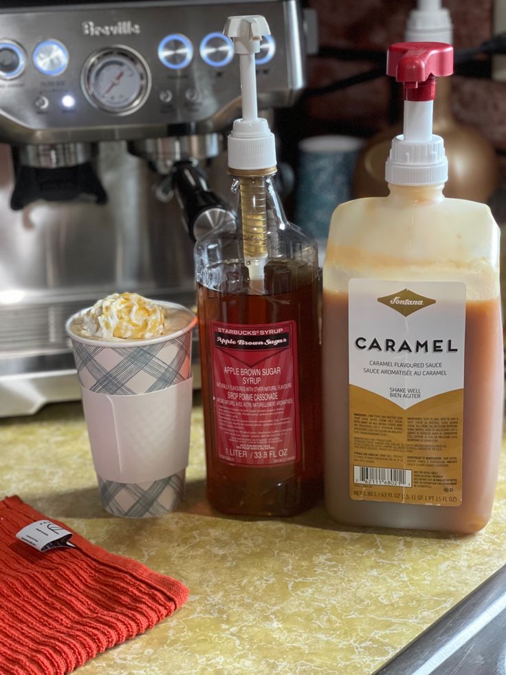 the coffee maker is next to some condiments and a bottle of caramel