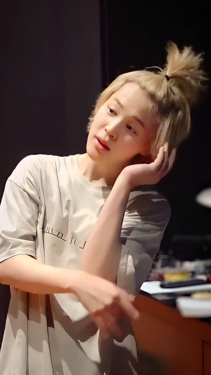 a young woman sitting in front of a desk with her hand on her head and looking off to the side