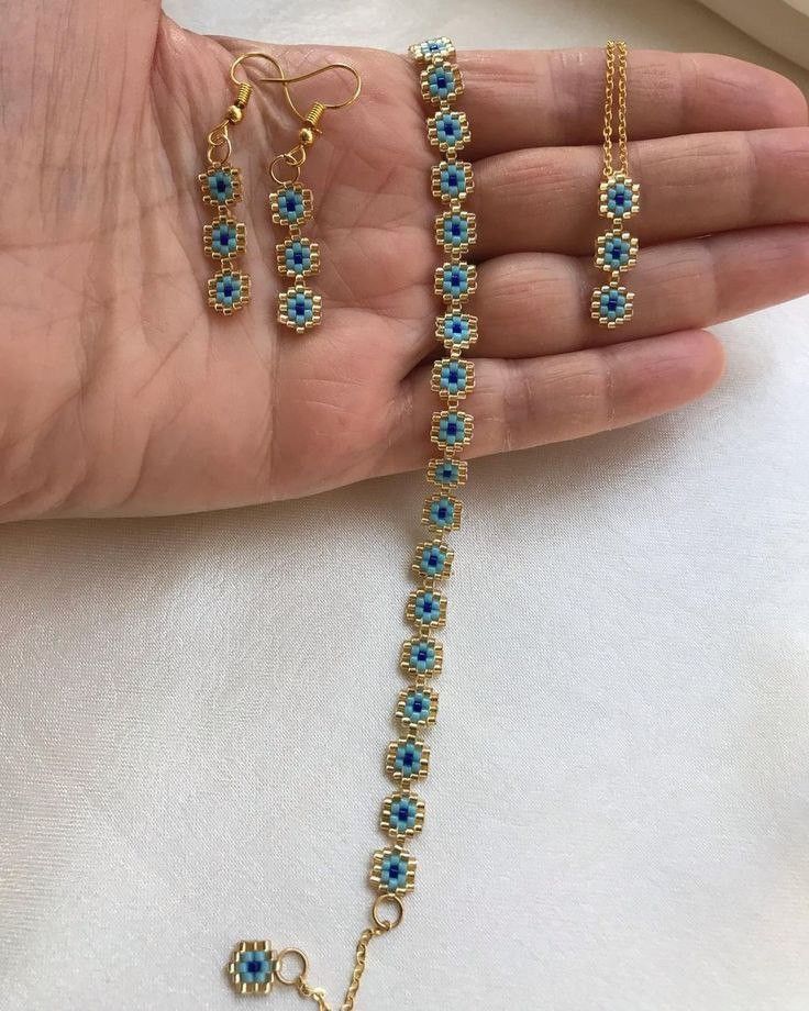 a woman's hand holding three pieces of gold and blue beaded bracelets