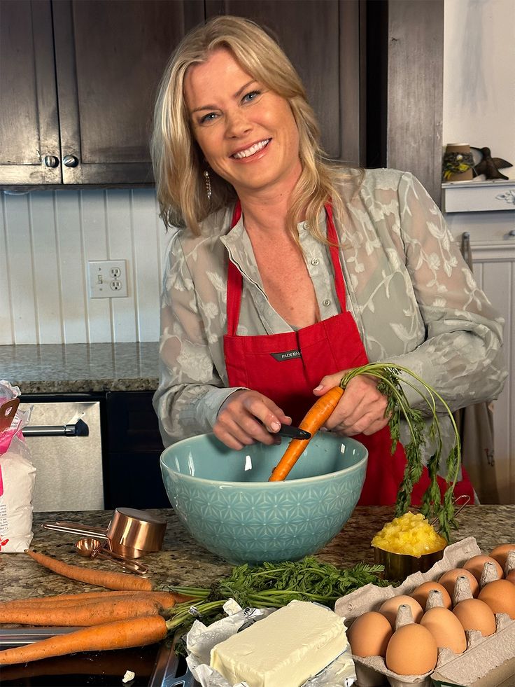 a woman in an apron preparing food on top of a kitchen counter with eggs and carrots