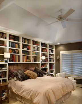 a bed sitting in a bedroom next to a book shelf filled with books on top of it