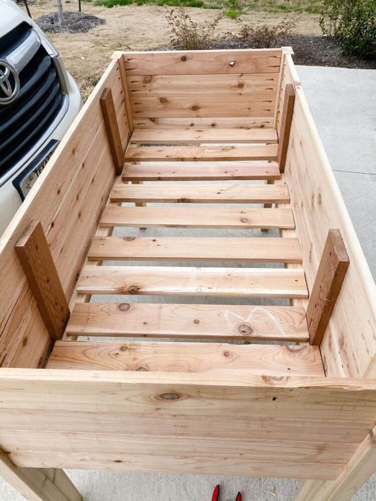 a wooden bed frame sitting next to a white car