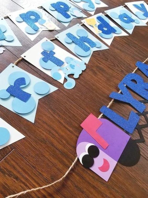 a wooden table topped with blue and purple paper cut out letters that spell out the word happy birthday