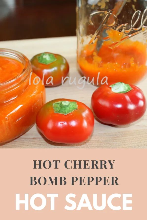 hot cherry bomb pepper sauce in a glass jar with tomatoes and peppers on the side