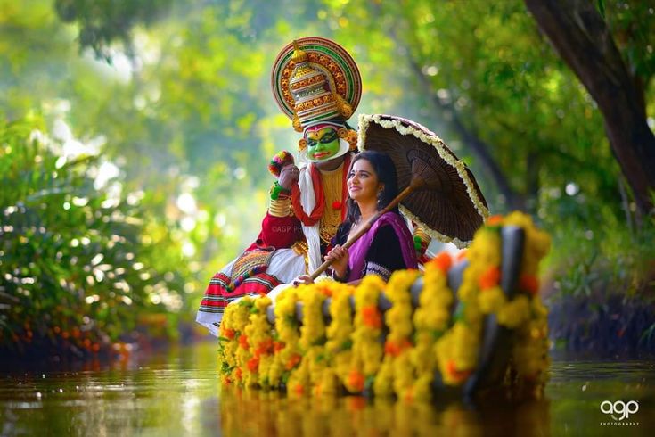 two people riding on the back of a boat down a river with flowers in front of them