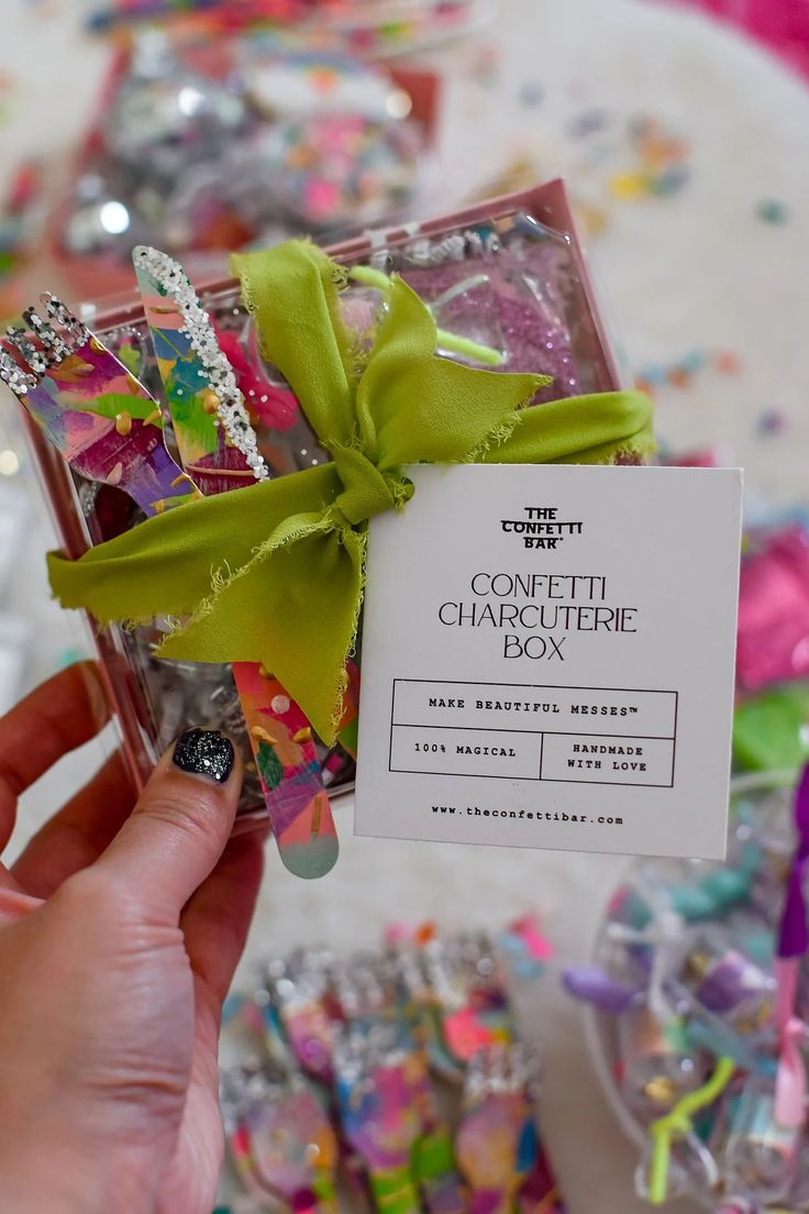 a person holding up a small box filled with confetti and other candies