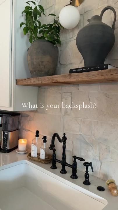 a kitchen sink sitting under a window next to a counter top with candles and soap dispensers on it