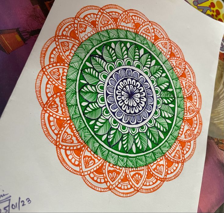 an orange, green and blue drawing on white paper next to other art work items