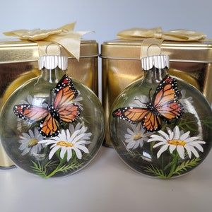 two glass christmas ornaments with butterflies on them