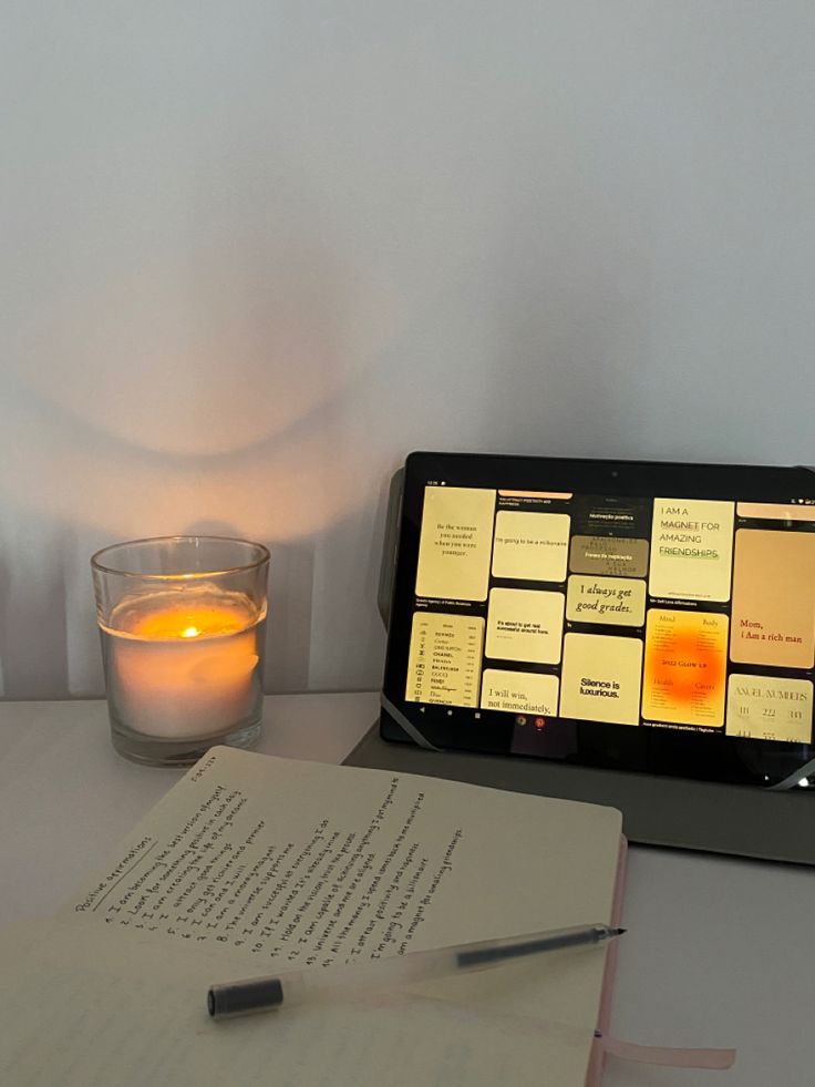 an open book next to a lit candle on a desk