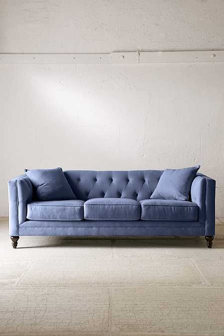 a blue couch sitting on top of a white floor next to a wall with a window