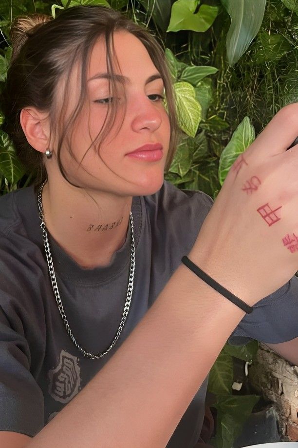 a woman sitting at a table with a plate of food in front of her and the word love tattooed on her wrist