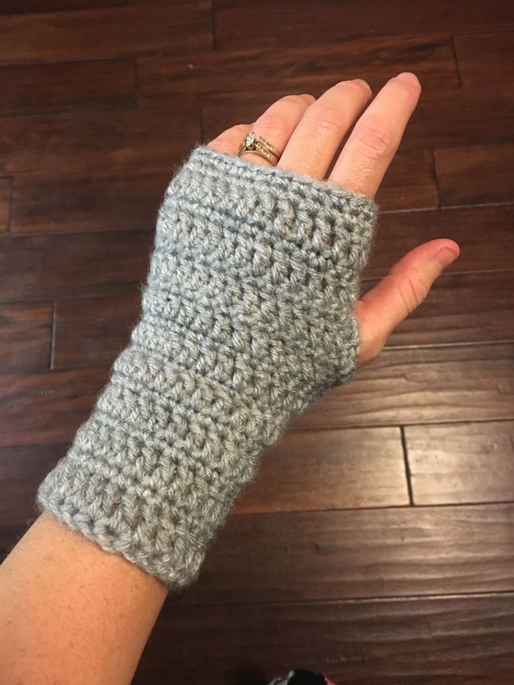 a woman's hand wearing a gray crochet wrist warmer