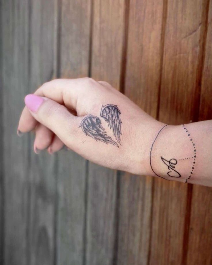 a woman's arm with two angel tattoos on her left wrist and the word love written in cursive writing