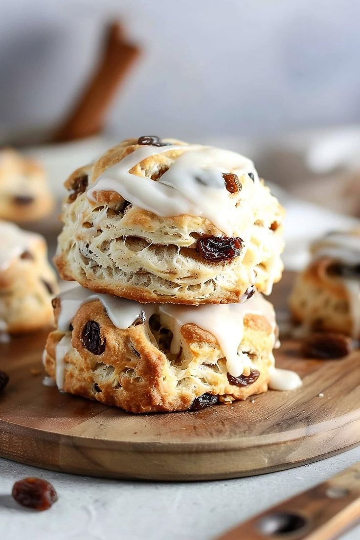 a stack of cookies with icing and raisins on a wooden plate next to a knife