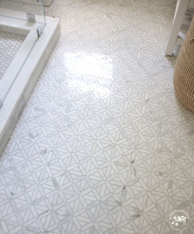 a bathroom with white marble flooring and tiled shower area in the corner, next to a toilet