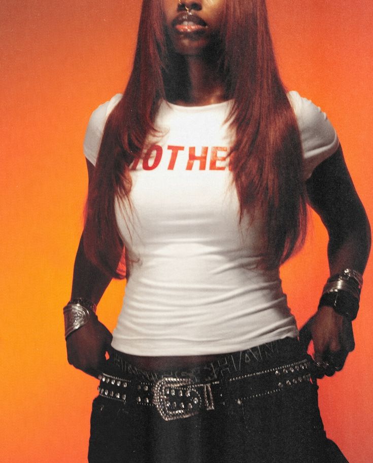 a woman with long red hair standing in front of an orange background