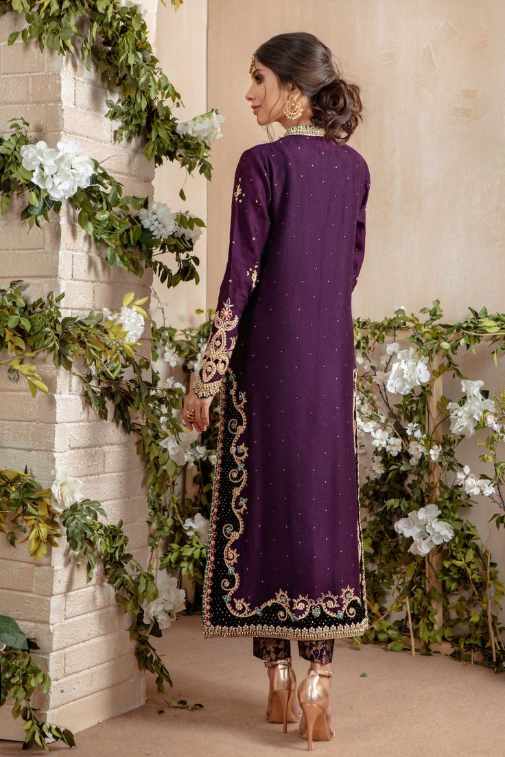 Over a canvas of aubergine hue, this jacquard silk net straight silhouette shirt features gold zardozi work,pearls, dabka, gota mix with contrasting resham, black velvet applique on hem & neckline, pointed sleeves for additional style quotient. This festive shirt is paired with jamawar pant and chiffon dupatta featuring hand embellished motifs, sprinkle sequins all over, Festive & Elegant, a must have for wedding festivities. Shirt Fabric: Pure Jacquard Silk Net Shirt Length: 48” (customisable, Elegant Purple Sets With Intricate Embroidery, Elegant Purple Salwar Kameez With Zari Work, Embellished Unstitched Kurta For Eid, Embellished Kurta For Eid, Elegant Purple Set With Zari Work, Elegant Purple Sets With Zari Work, Elegant Purple Salwar Kameez For Eid, Elegant Purple Unstitched Suit For Formal Occasions, Formal Purple Sets With Zari Work