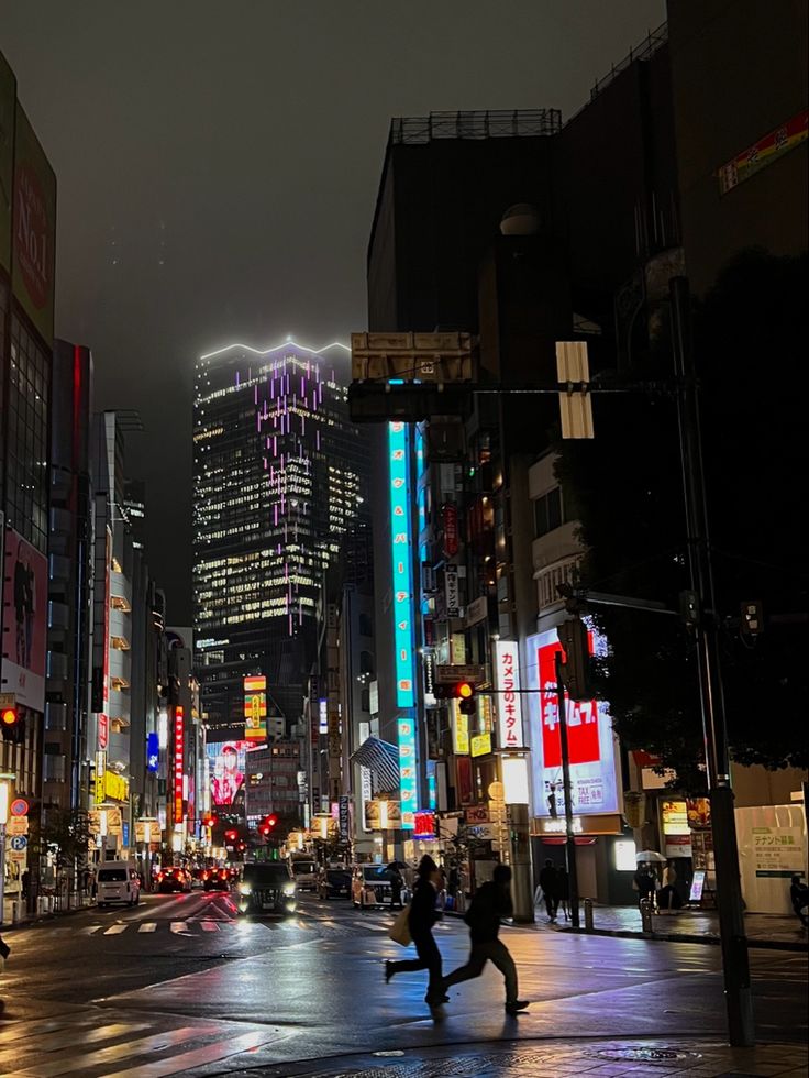 two people are running in the rain on a city street with tall buildings and neon lights