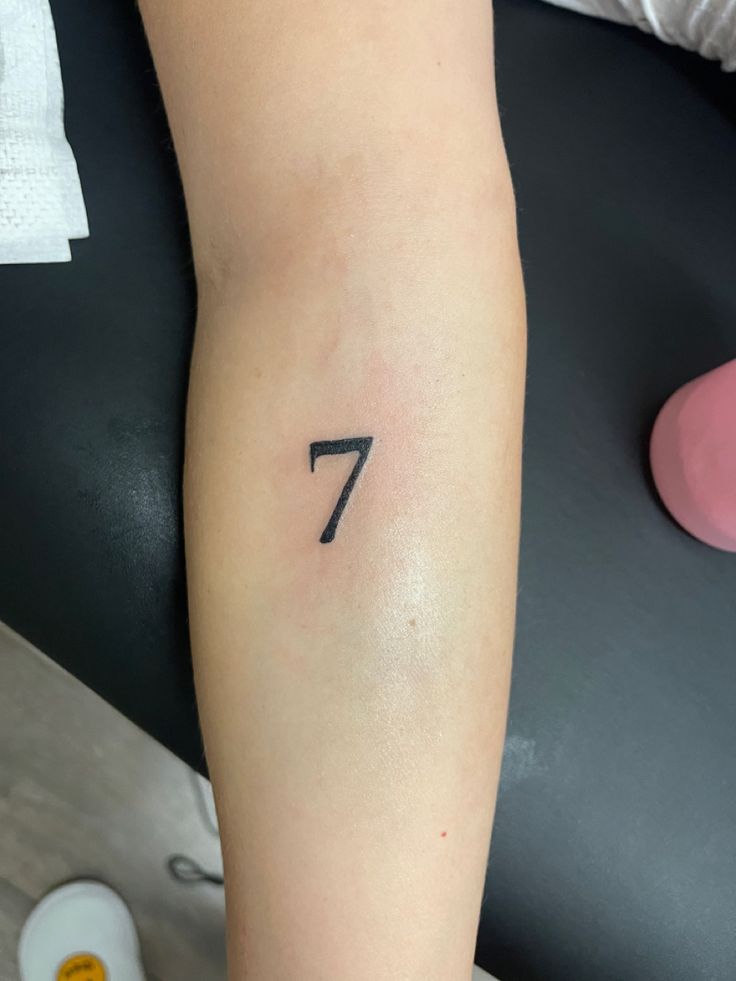 a woman's arm with the number seven tattoo on it