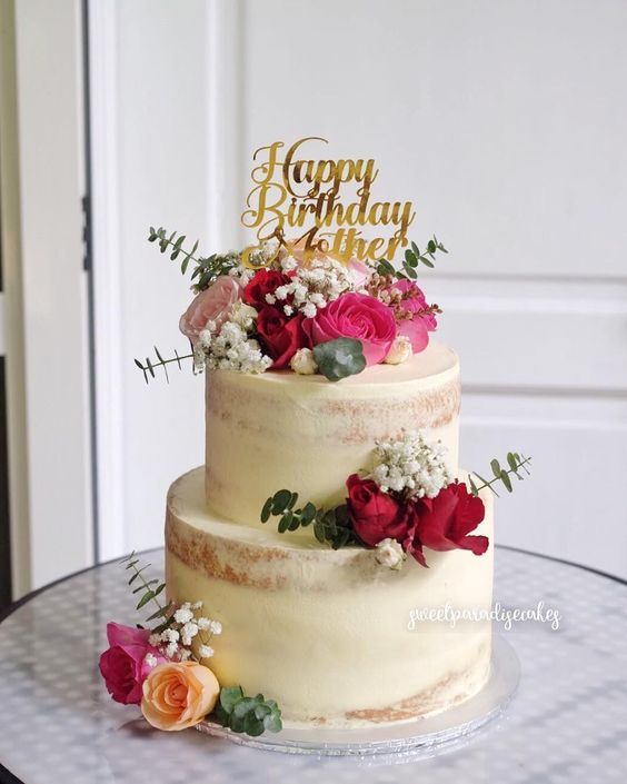 a three tiered cake with flowers on the top and happy birthday written on it