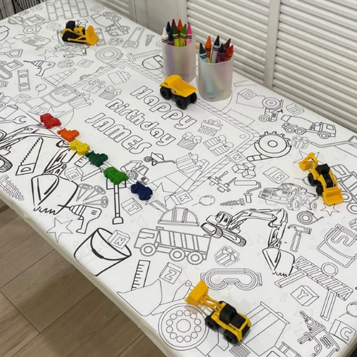 the table is covered with construction themed paper and crayons on top of it