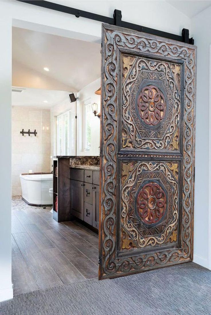 an ornate wooden door is open to reveal a bathroom with a large tub in the background