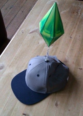 a baseball cap with a green kite hanging from it's side on a wooden table