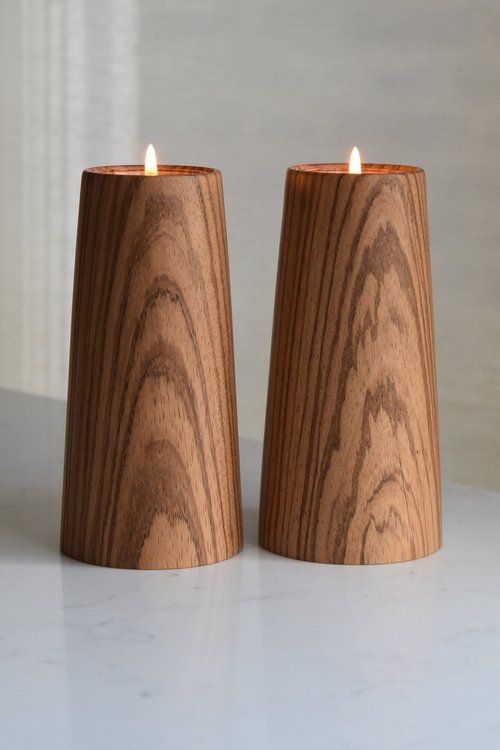 two wooden candle holders sitting on top of a white counter