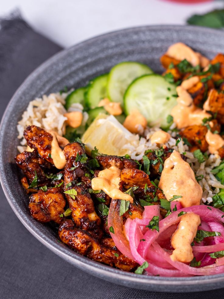 a close up of a bowl of food with rice and veggies on the side