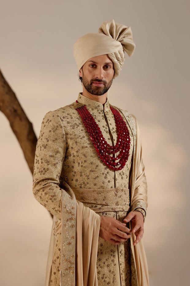 Sandune Sherwani Set | Jatin Malik Introducing our exquisite sand grey all-over hand-embroidered sherwani set, a true work of art. The foundation of this sherwani is crafted with golden zari threads, creating a luxurious base texture. The second tier is highlighted with intricate gold dabka work, accentuating the overall brilliance. This ensemble is perfectly complemented by a tone-on-tone hand-embroidered stole and safa, adding an extra layer of elegance and sophistication. Perfect for making a grand statement, this sherwani set embodies opulence and refined craftsmanship. Included in purchase: Sherwani, Kurta, Churidar, Stole, Safa, Cummerbund Product Specification Color: Sand grey Fabric: Linen silk Occasion: Engagement, Wedding, Bridal, Reception Style: Sherwani, Kurta, Churidar, Safa, Ceremonial Beige Sherwani With Traditional Drape, Ceremonial Beige Bandhgala With Resham Embroidery, Beige Bandhgala With Naqshi For Reception, Ceremonial Beige Bandhgala With Intricate Embroidery, Traditional Bandhgala With Gold Embroidery In Raw Silk, Traditional Sherwani With Naqshi For Reception, Ceremonial Raw Silk Sherwani With Cutdana, Gold Sherwani With Zari Work In Kundan, Traditional Gold Sherwani With Cutdana