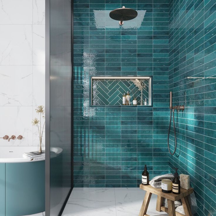 a bathroom with blue tiles and a wooden stool in the corner, along with a shower