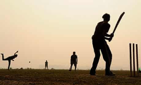 a man holding a baseball bat standing next to a ball on top of a field