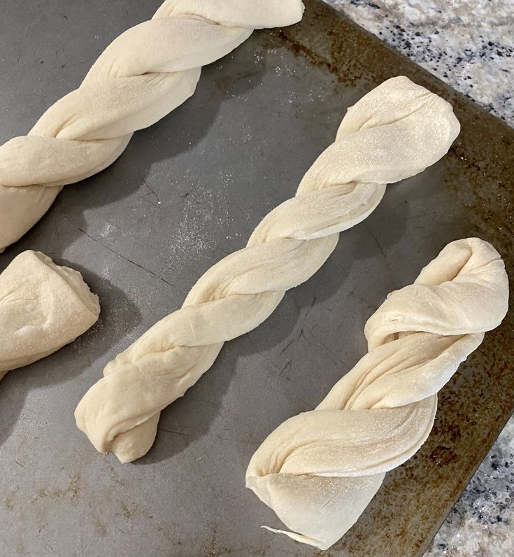 three loaves of bread sitting on top of a baking sheet in the process of being made