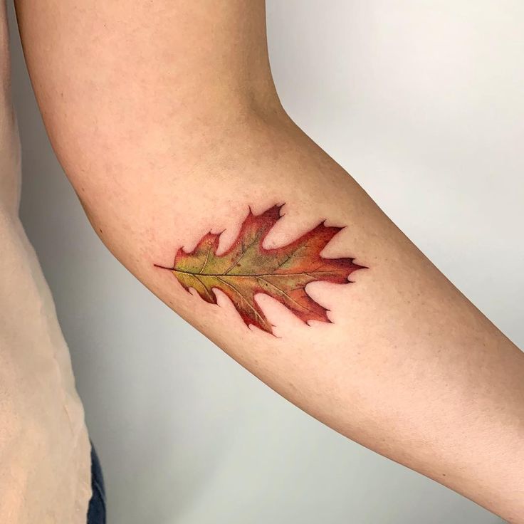 a person with a tattoo on their arm that has a maple leaf painted on it