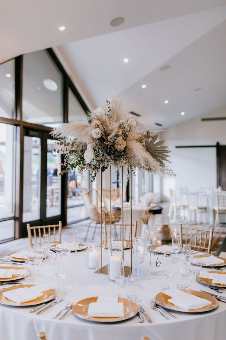 an elegant centerpiece with feathers and flowers on a table