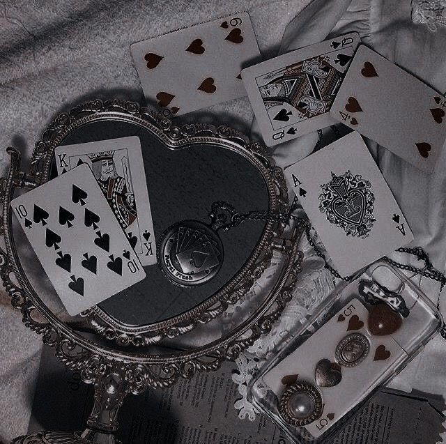 playing cards are laying on the bed next to an antique mirror and keychain