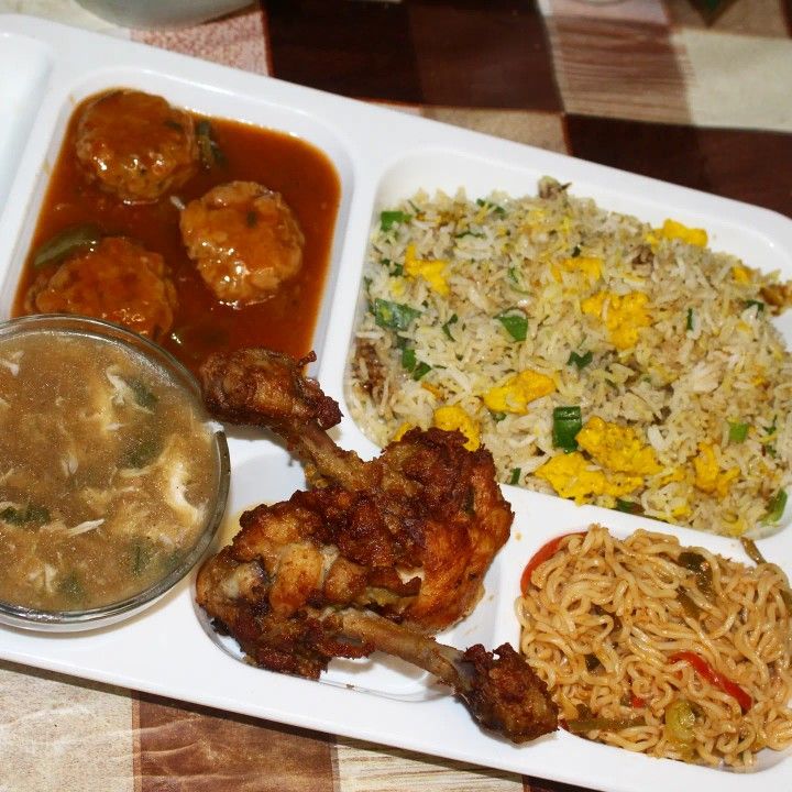 a white plate topped with different types of food next to a bowl of rice and sauce