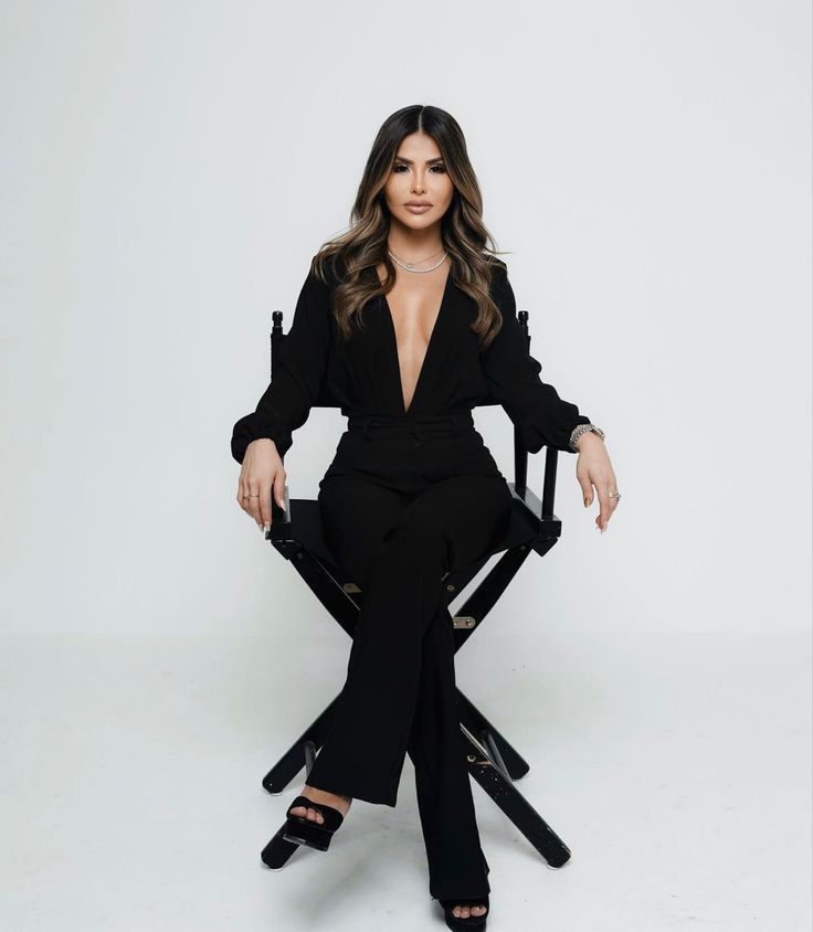 an image of a woman sitting in a chair with her legs crossed and wearing black