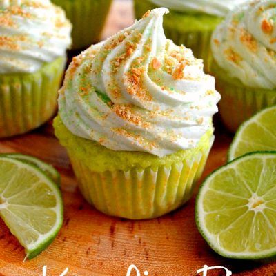 lime cupcakes with white frosting and orange sprinkles on a cutting board