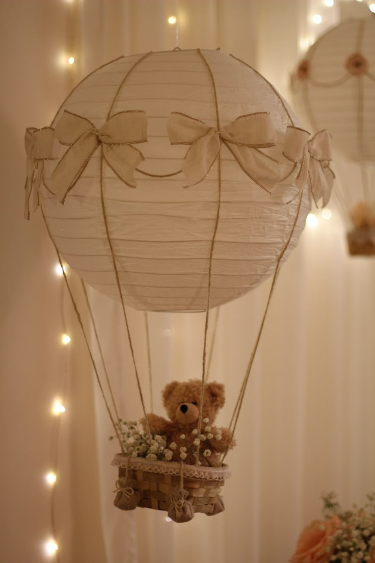 a teddy bear in a hot air balloon with lights on the wall behind it,