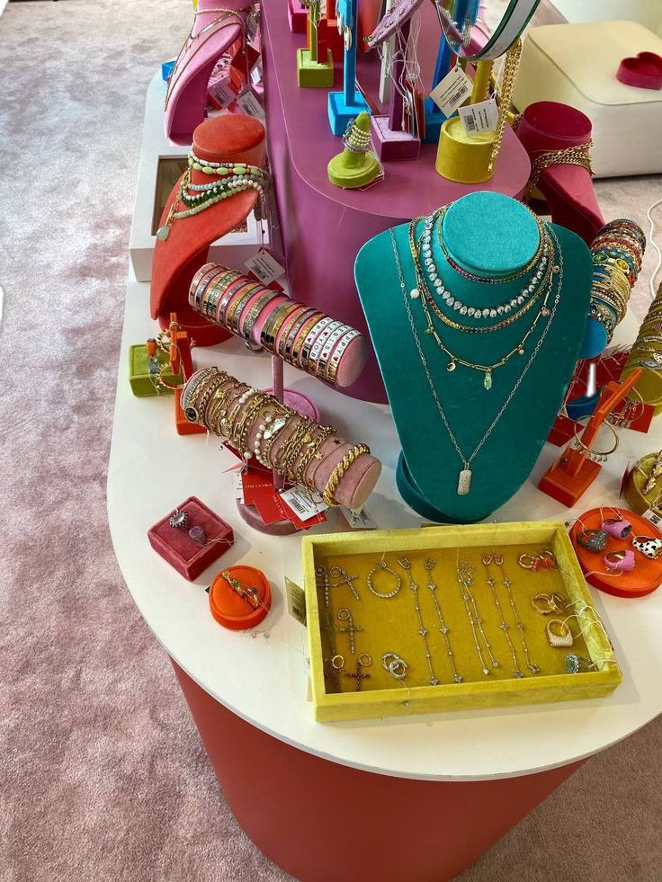 an assortment of jewelry is displayed on a table in a room with carpeted flooring